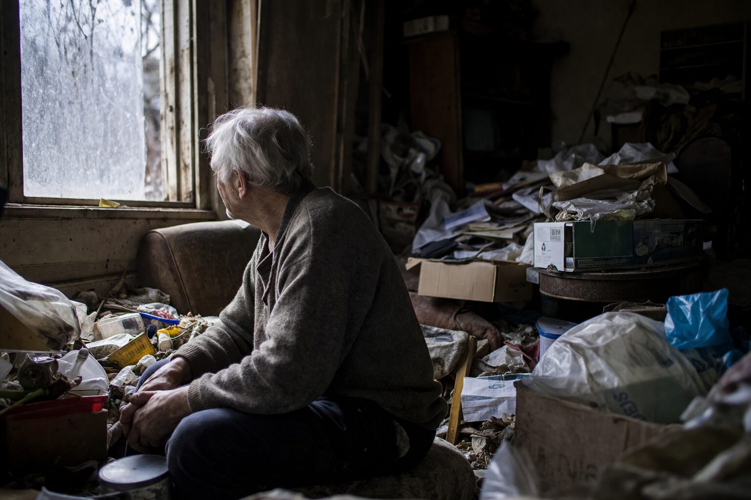 Patient âgé en situation d’isolement relationnel dans un logement très encombré, illustrant l’aggravation de l’incurie liée aux syndromes de Diogène, Noé ou Korsakoff