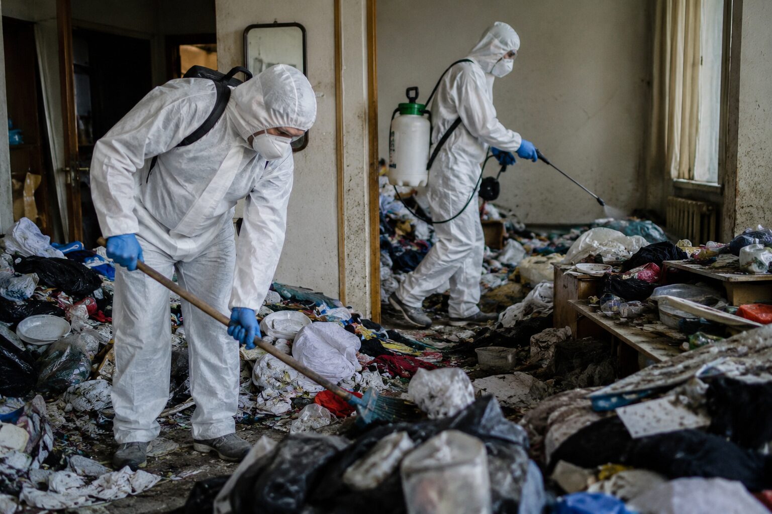 Professionnels en combinaison réalisant un nettoyage Diogène et une désinsectisation dans un logement très encombré pour éviter une recontamination