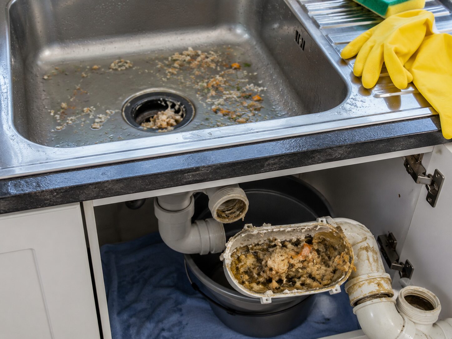 Évier de cuisine bouché avec siphon démonté rempli de graisse figée et de restes alimentaires