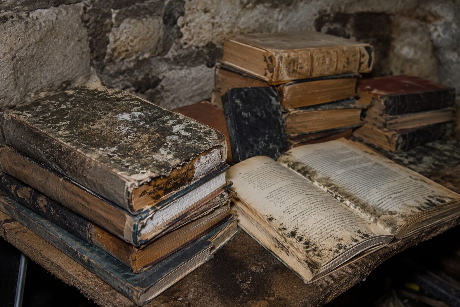 Livres anciens moisis retrouvés dans une cave humide avant nettoyage, tri et évacuation