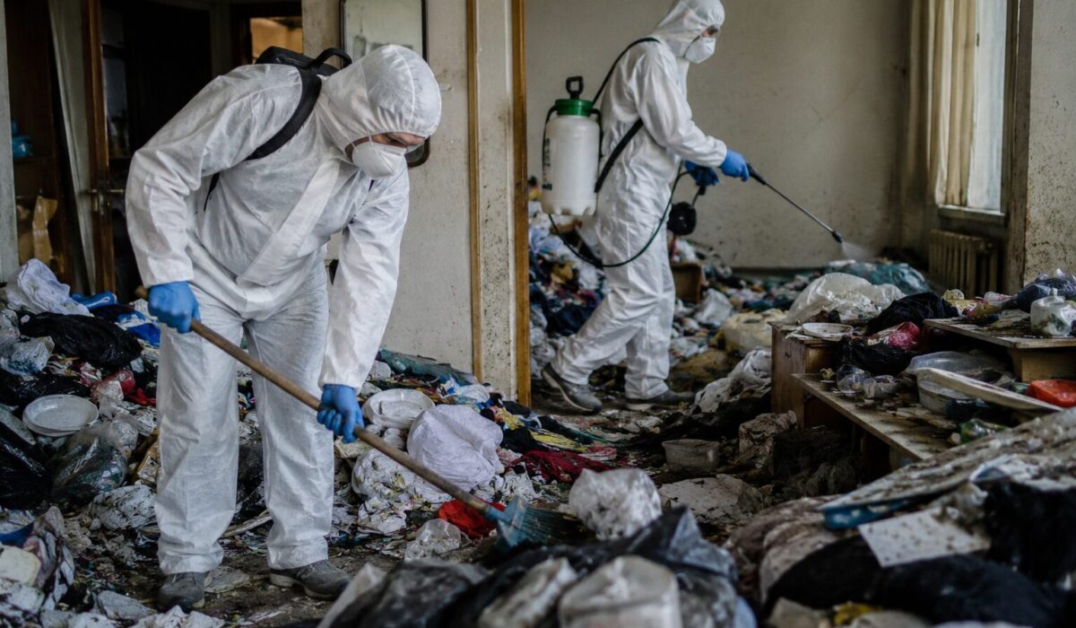 Professionnels en combinaison réalisant un nettoyage Diogène et une désinsectisation dans un logement très encombré pour éviter une recontamination