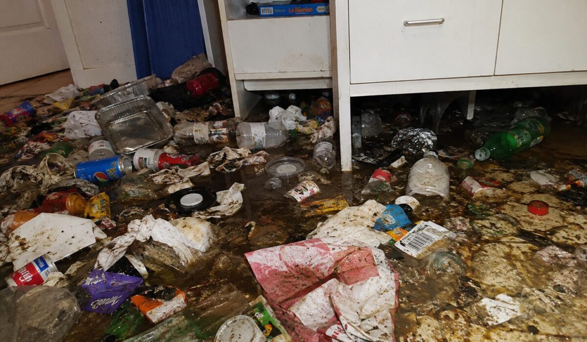 Sol très sale avec déchets, liquides de poubelle et résidus ayant coulé sous les meubles d’un logement à nettoyer